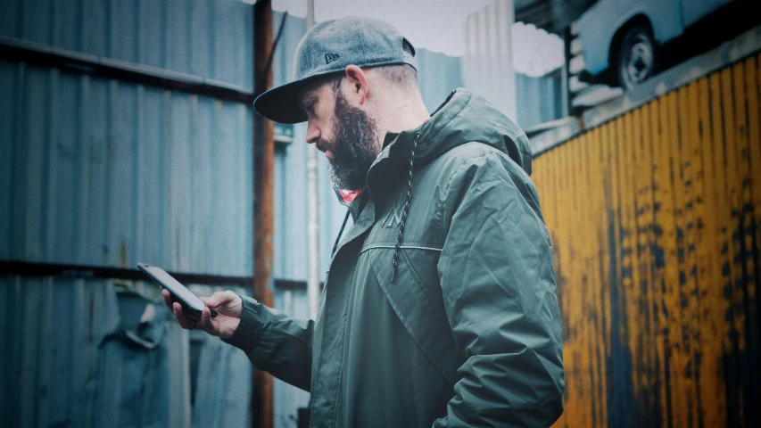 a man standing next to a fence holding a tablet