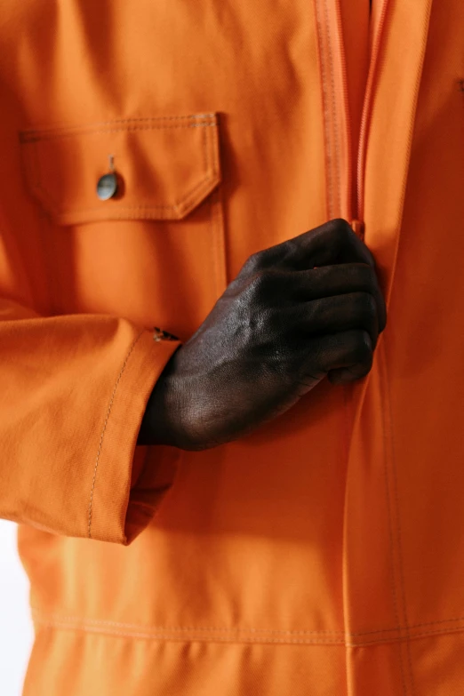 a hand of a person wearing an orange uniform