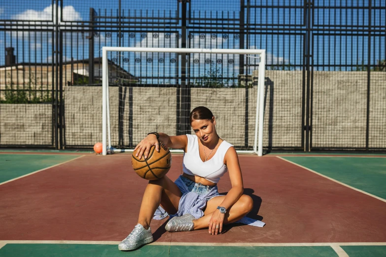 a woman sitting on a court with a basketball in her hand