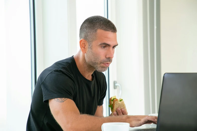 the man is working on his computer while eating