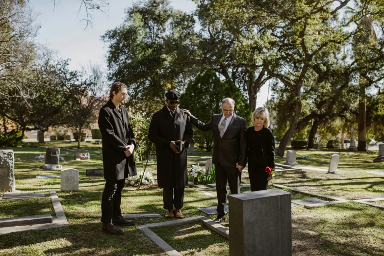 people stand in a graveyard near gravestones