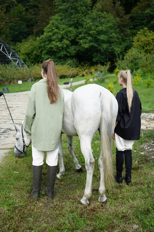 two women are standing next to a horse