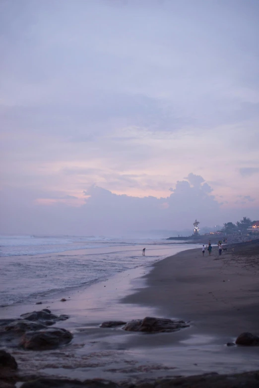 some people walking down the beach next to the water