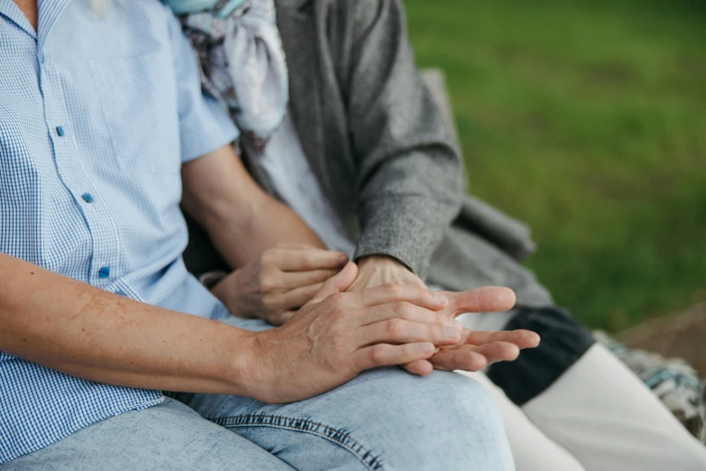 a close up of two people sitting down holding hands