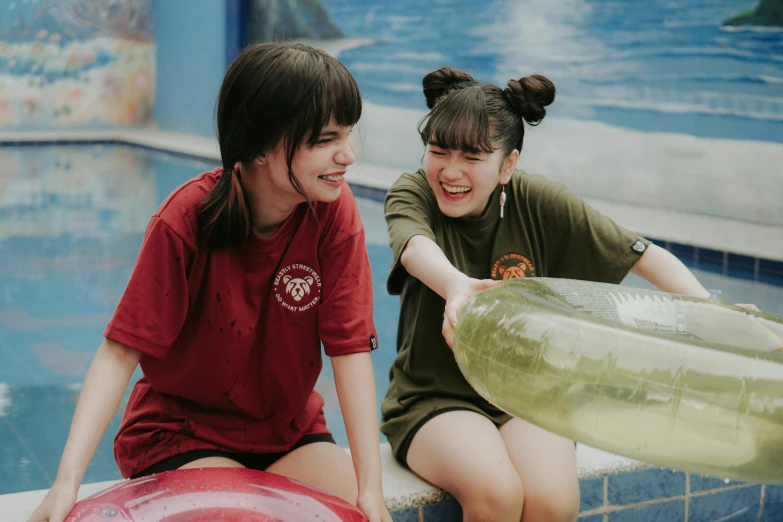 two women smiling next to a swimming pool