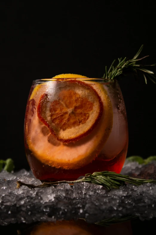an orange slice in a glass with a rosemary sprig garnishes on top