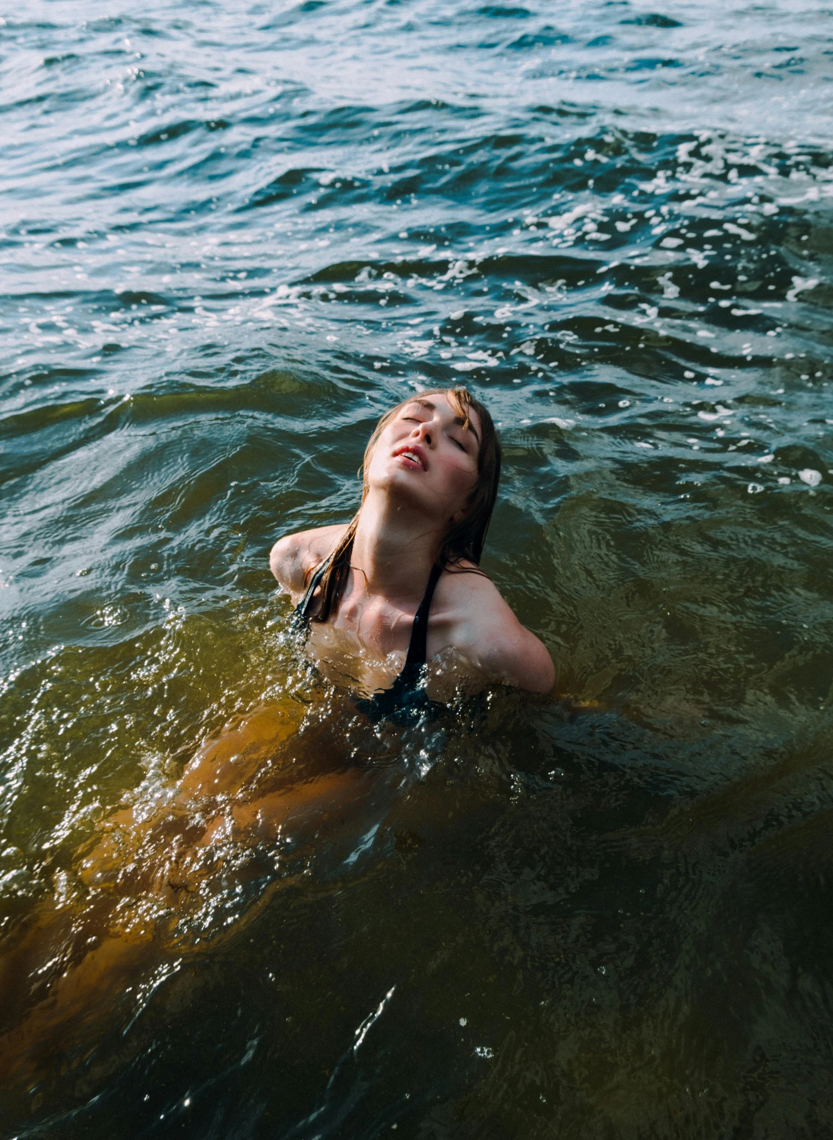 a young woman wearing a bikini and swimming in the ocean