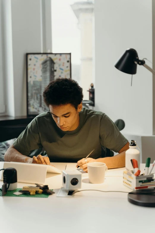 a man working at a desk with a laptop and coffee mug