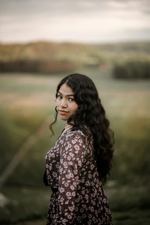 a young woman with long hair standing in the field