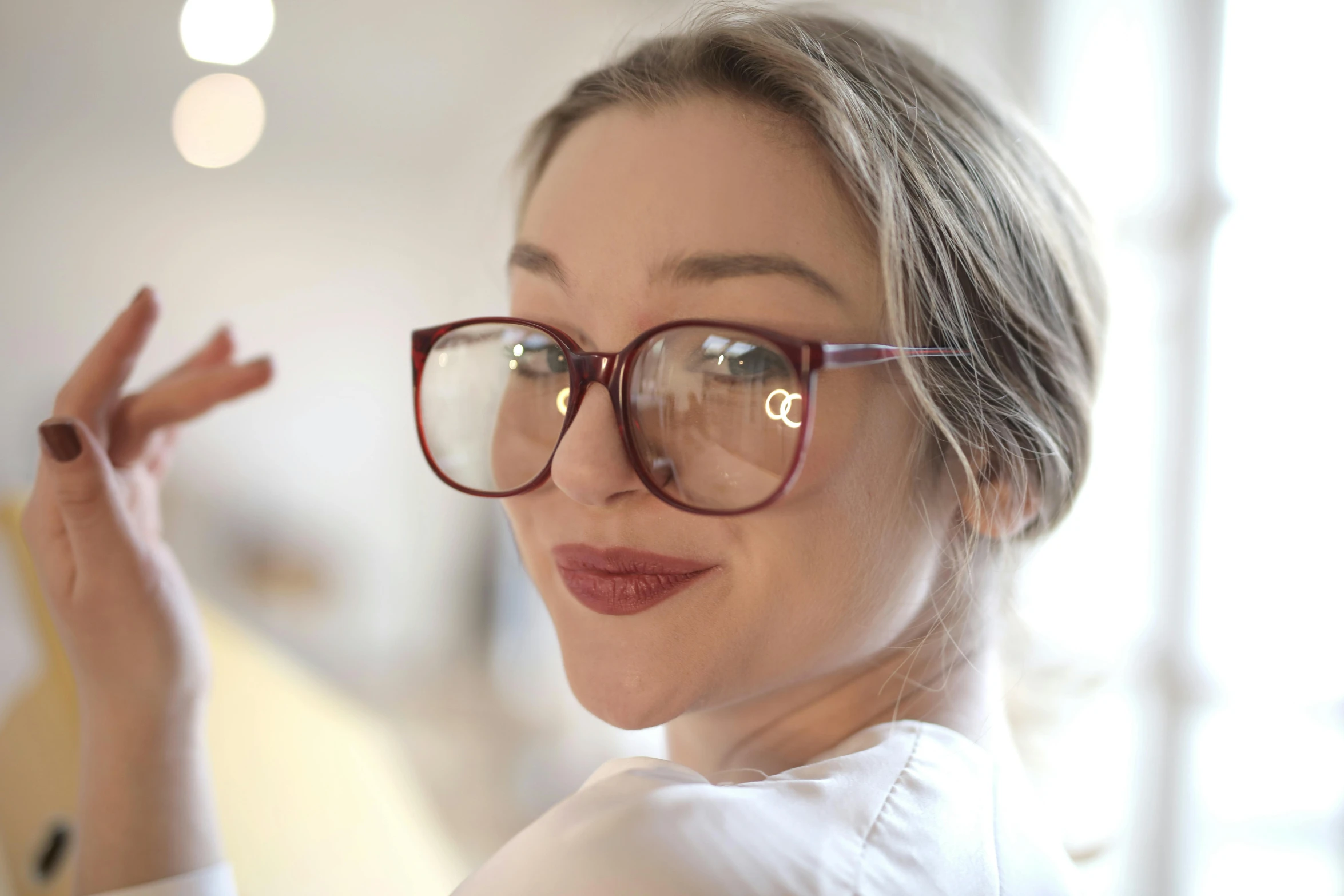 a woman wearing glasses and pointing to soing with her finger