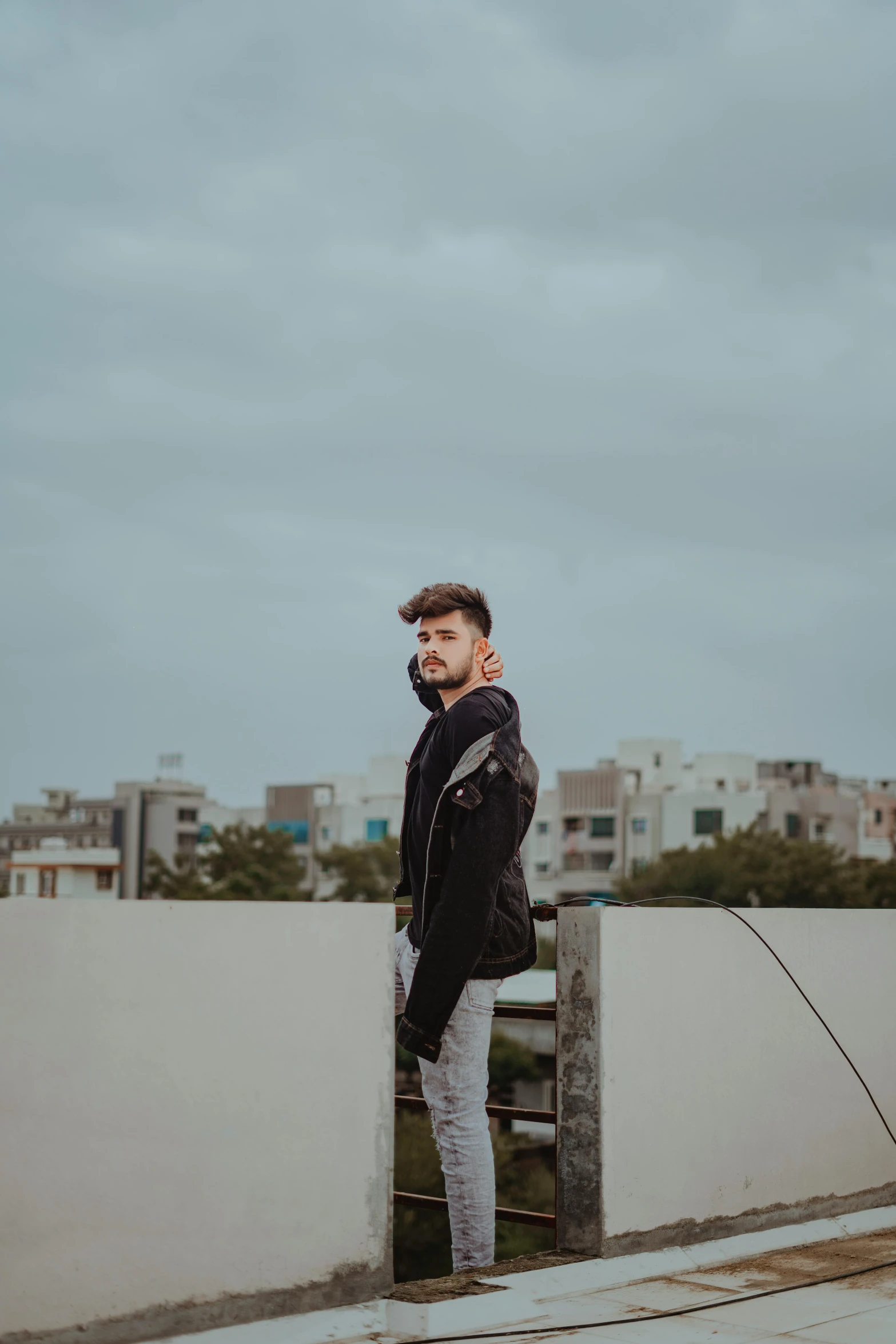 man standing with his legs crossed on a fence