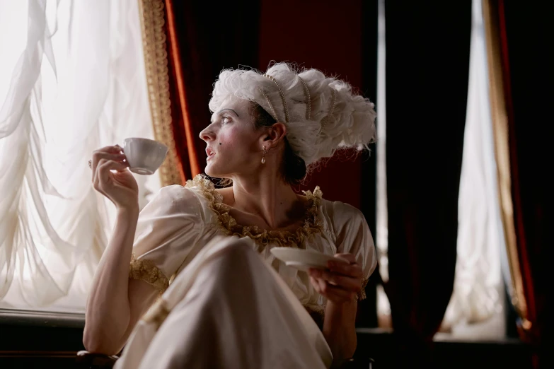 a woman with long hair sitting and drinking from a cup