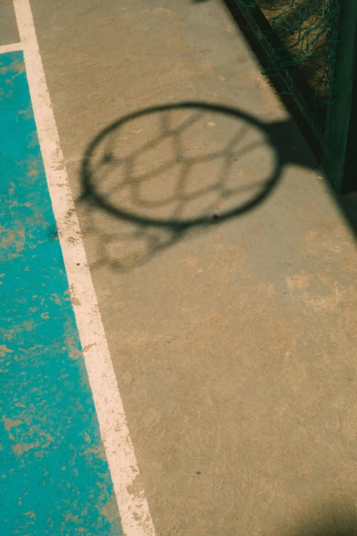 a shadow on a cement sidewalk with a tennis racket and ball