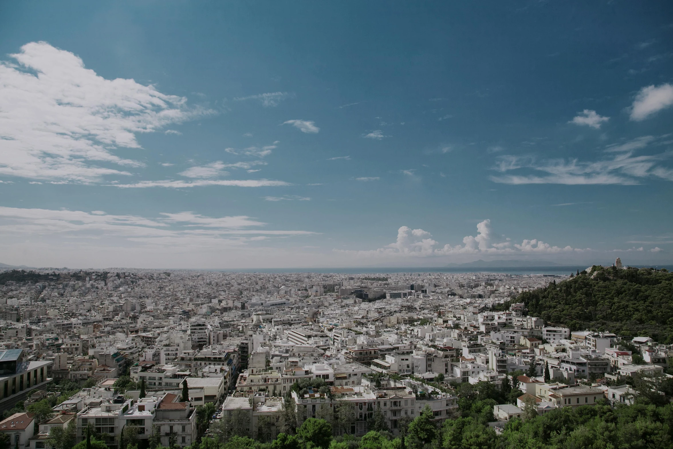 a large city with white buildings sitting below a cloudy blue sky