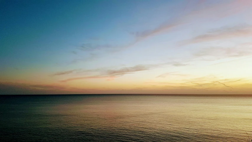 the ocean with a plane flying in the distance