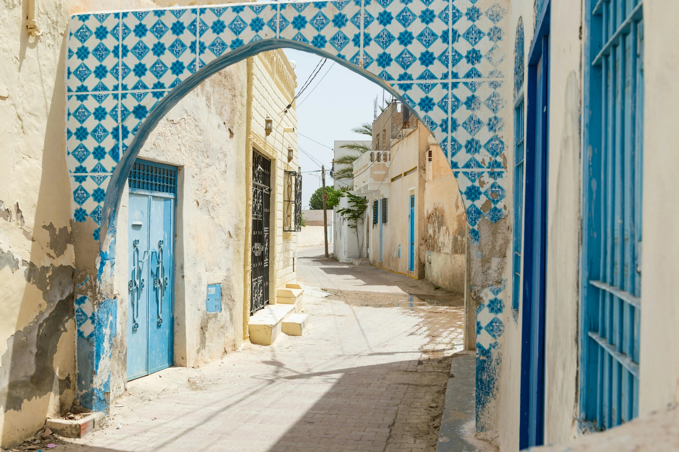 an arch leads into an alley with blue doors