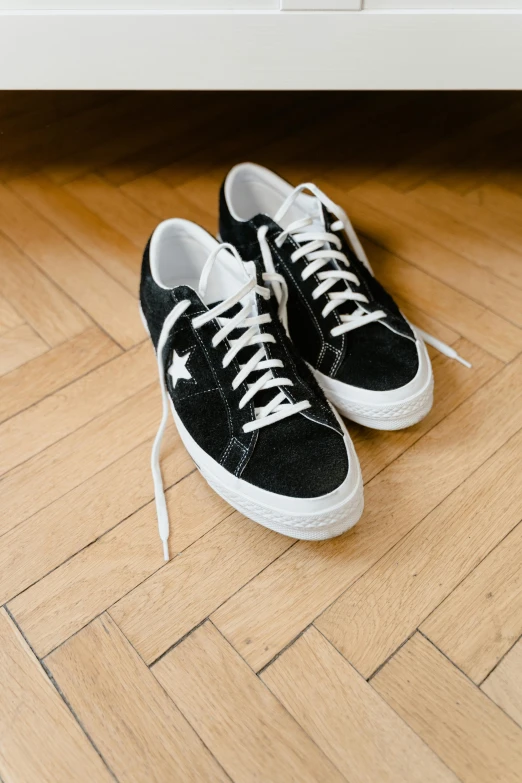 a pair of black sneakers sits on the wooden floor