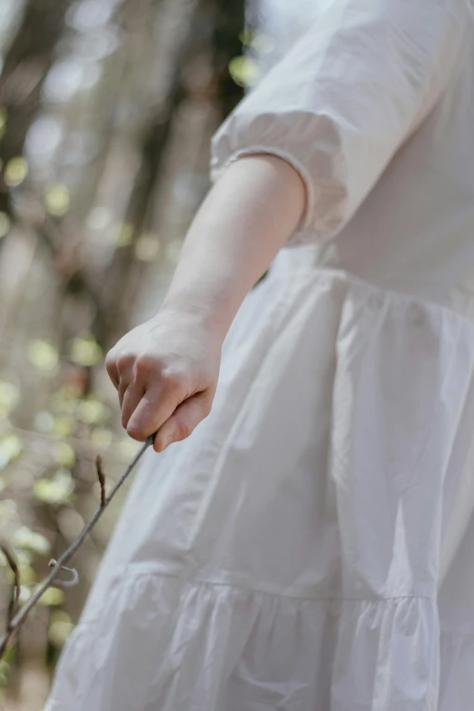 a person with her hands in the air holding a twig