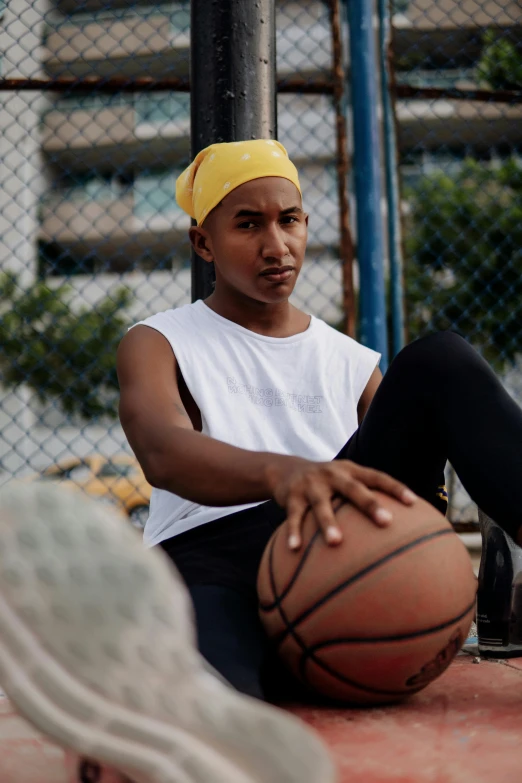 a young man sits with his feet on a basketball ball