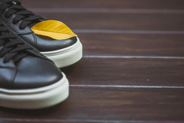 black sneakers with a yellow top sit on the floor