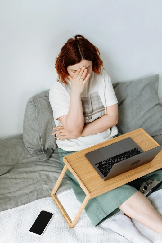 a woman is sitting on the bed in front of a table