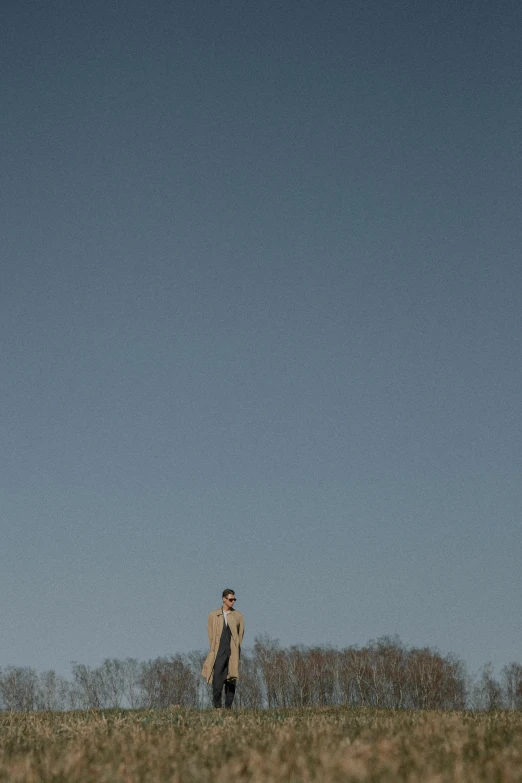 a man standing on top of a hill holding onto the strings of a kite