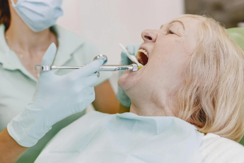 two dentists smiling while one woman is taking an oral rub with her mouth