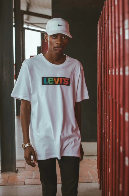 a young man stands next to the wall in front of his building