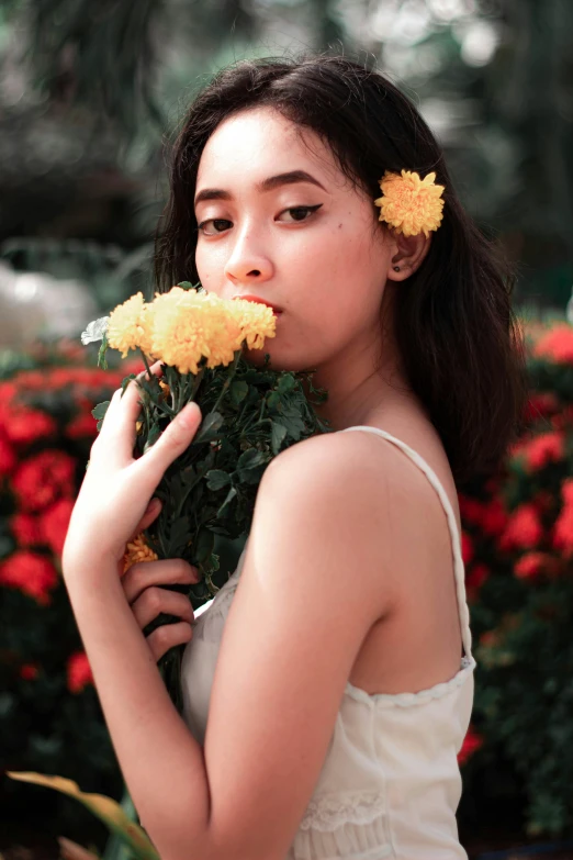 a woman smelling flowers in a garden with red and yellow flowers