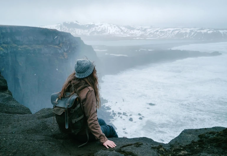 a person overlooking the ocean sitting on some rocks