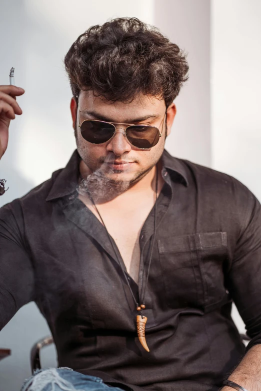 a man wearing a black shirt and sunglasses smoking cigarette