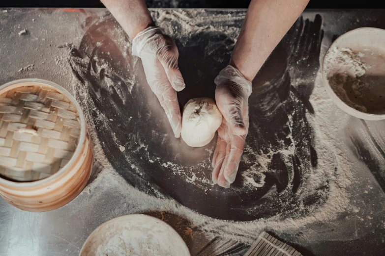 someone working with their hands while dough sits on a counter