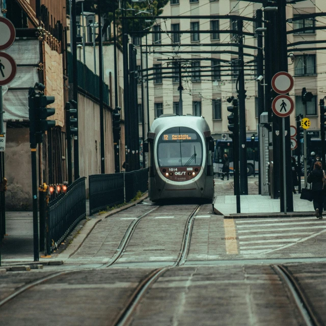 an electric train moving down a track in the middle of town