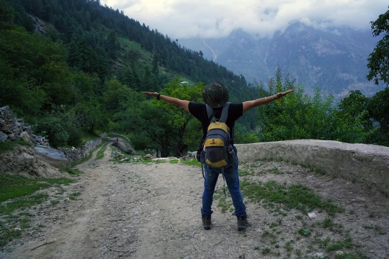 a person is standing on a dirt road with their arms raised