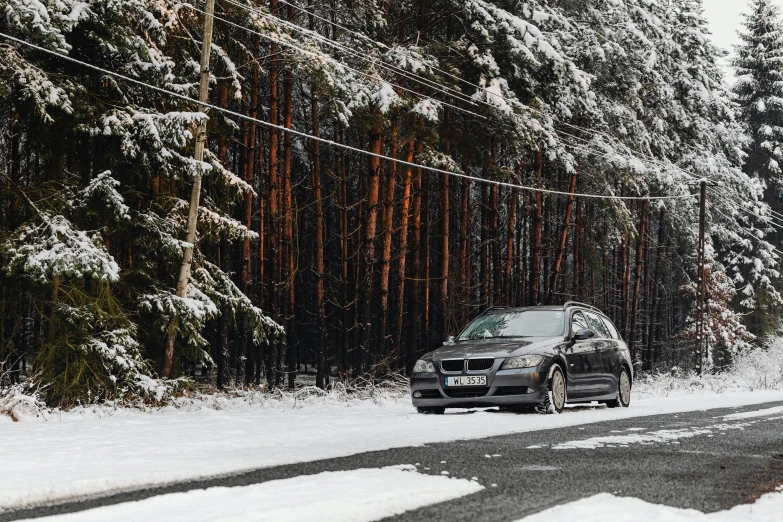 the small car is driving on the snow covered road