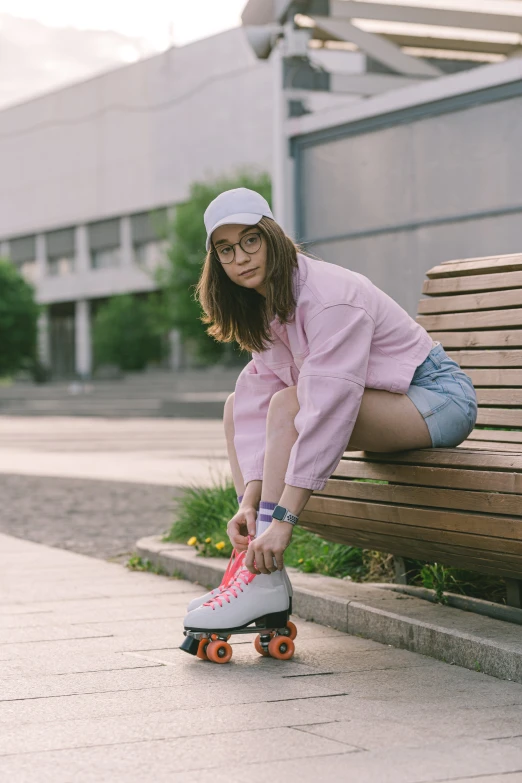 woman in pink shirt and black cap on skateboard next to wooden bench