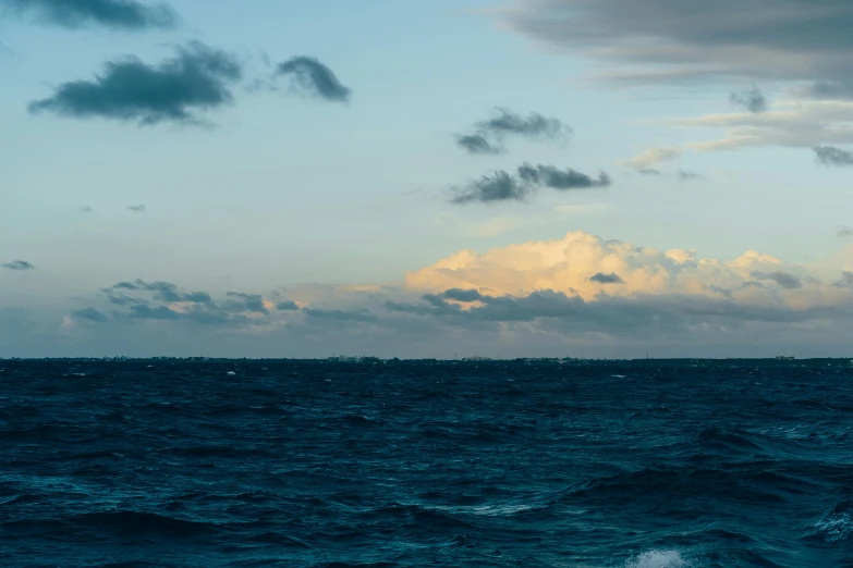 a large body of water sitting under a cloudy blue sky