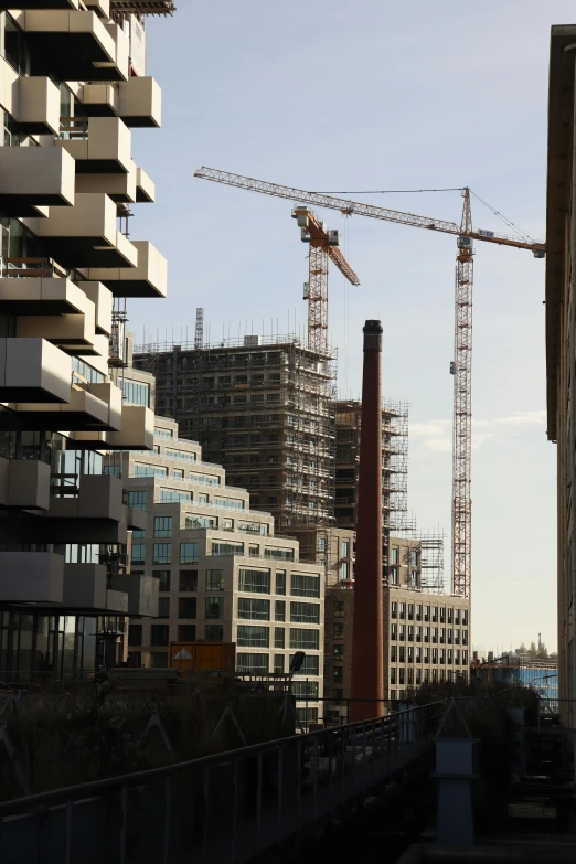 construction cranes near a row of buildings under construction