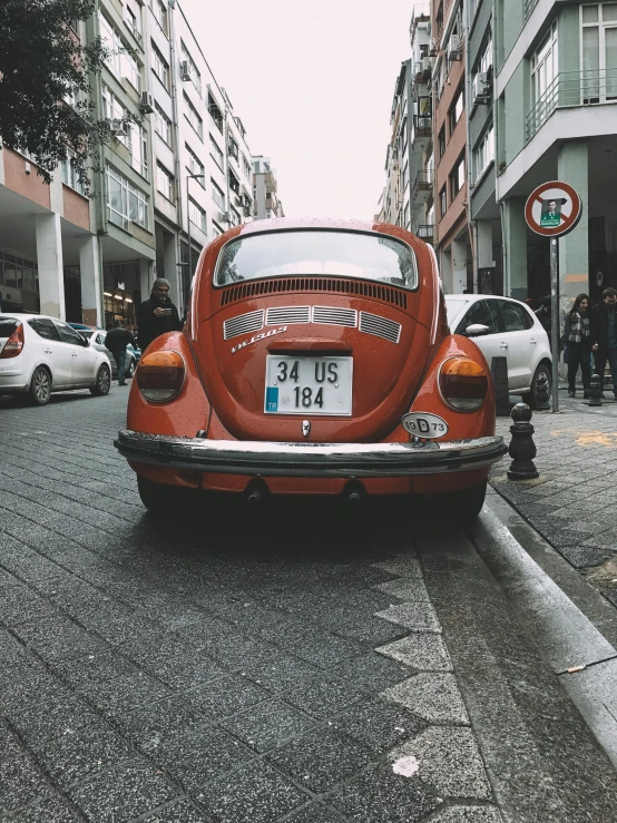 old red beetle parked on the street in front of tall buildings