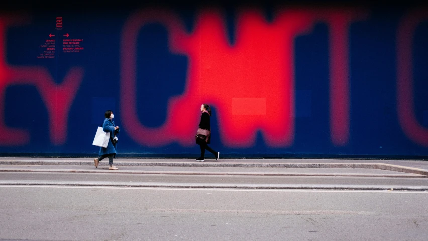 two people crossing the street in front of an advertit