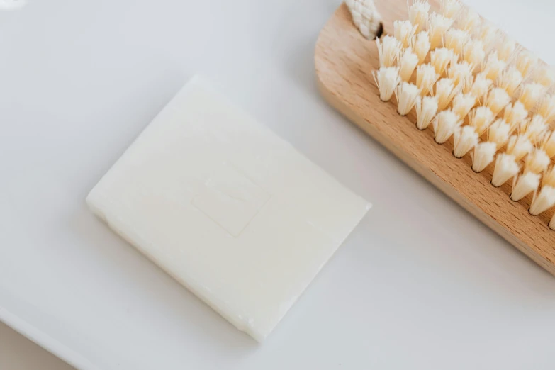 a body soap and brush on a white surface