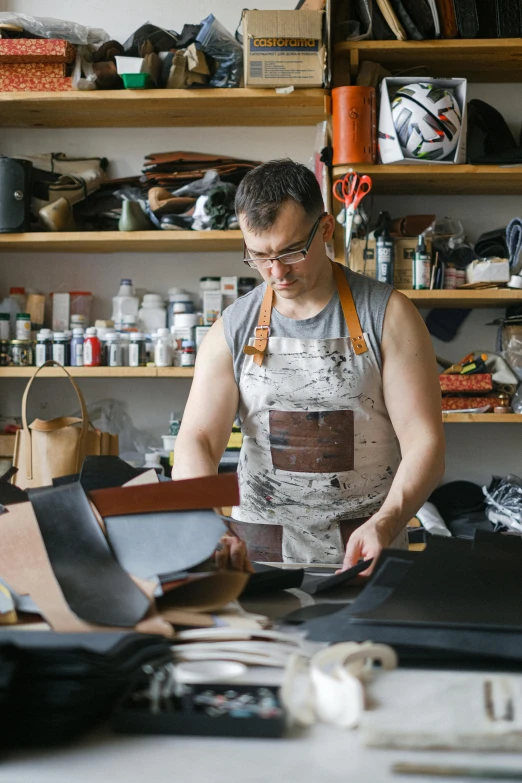 a man with an apron and glasses working on leather