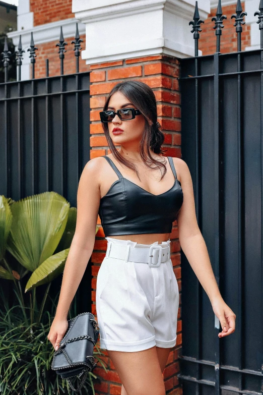 a woman in white shorts walking past a brick wall