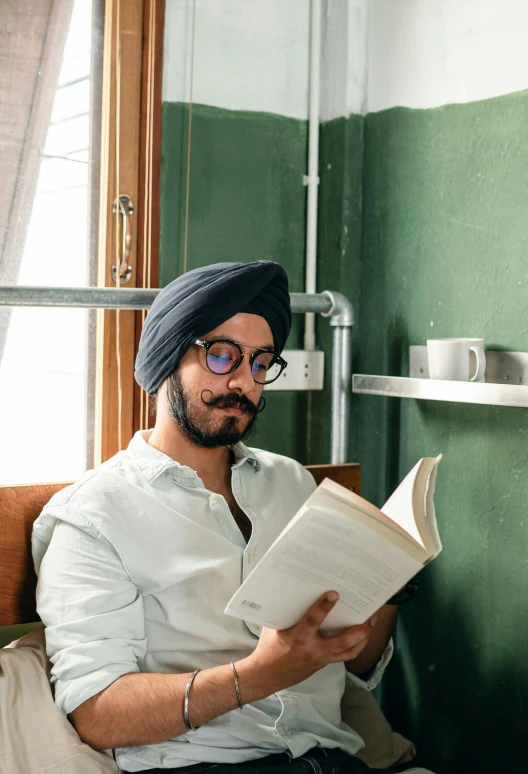 a man reading a book while wearing a turban