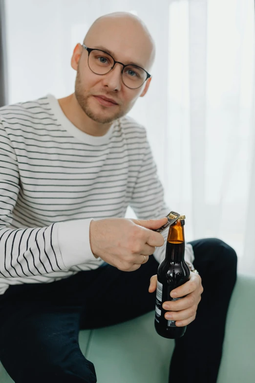 a man holding a beer next to a green couch