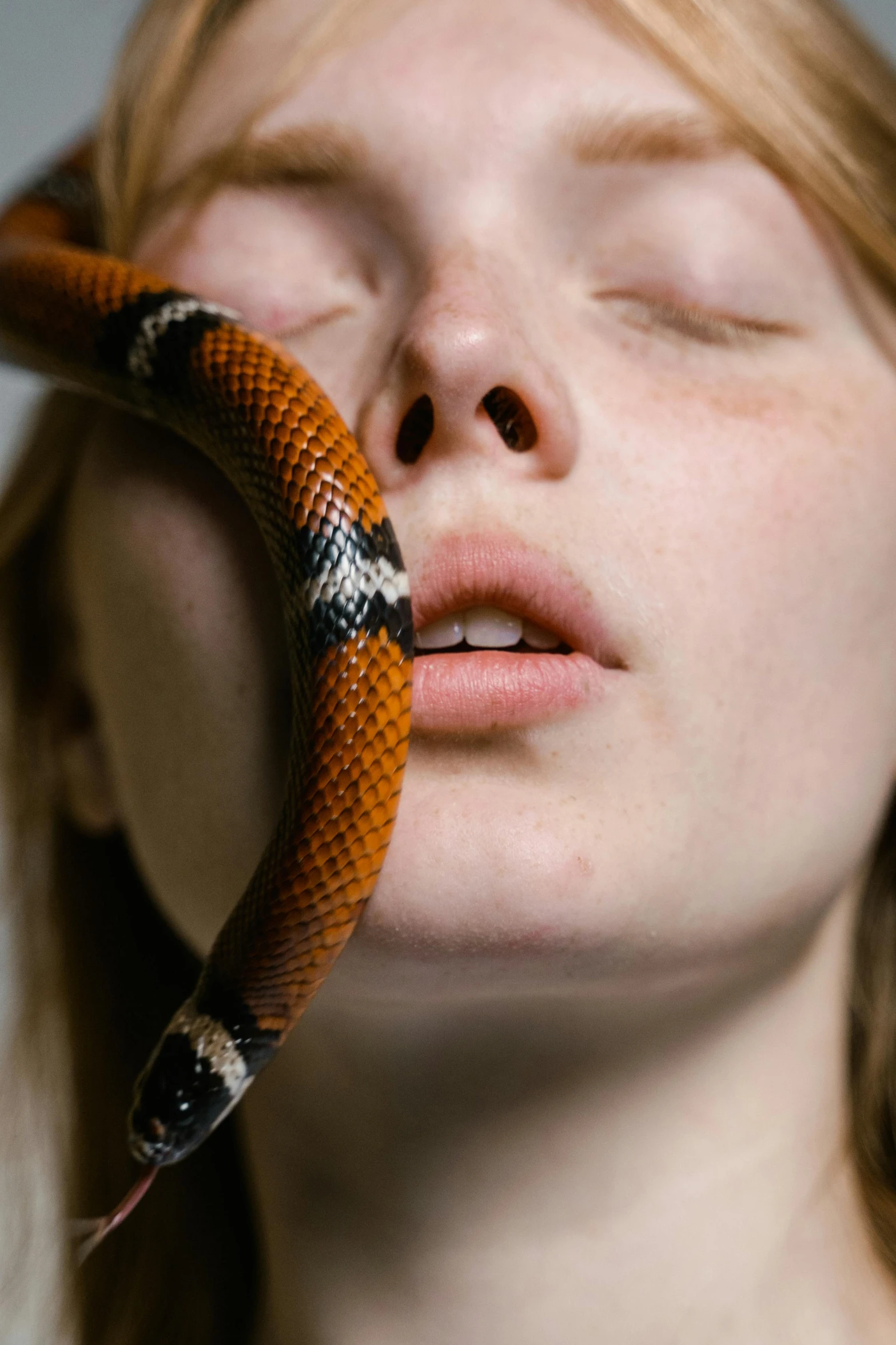 a woman sleeping with her eyes closed and her head curled up behind a snake