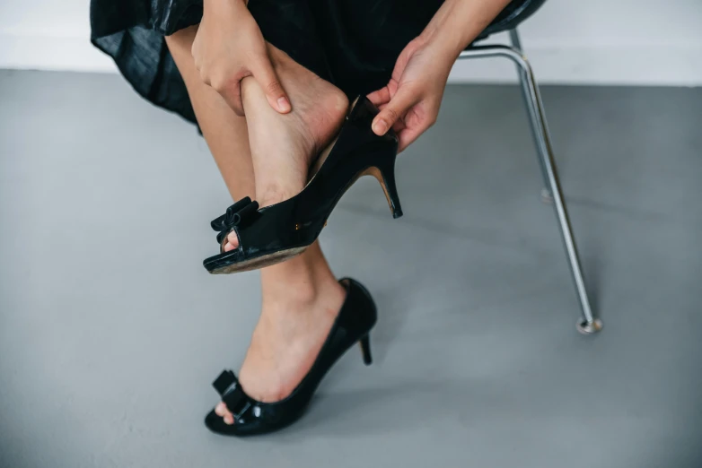 a woman with her leg propped up on a chair while tying her high heels