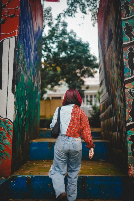 a woman in overalls walks down some steps with paintings