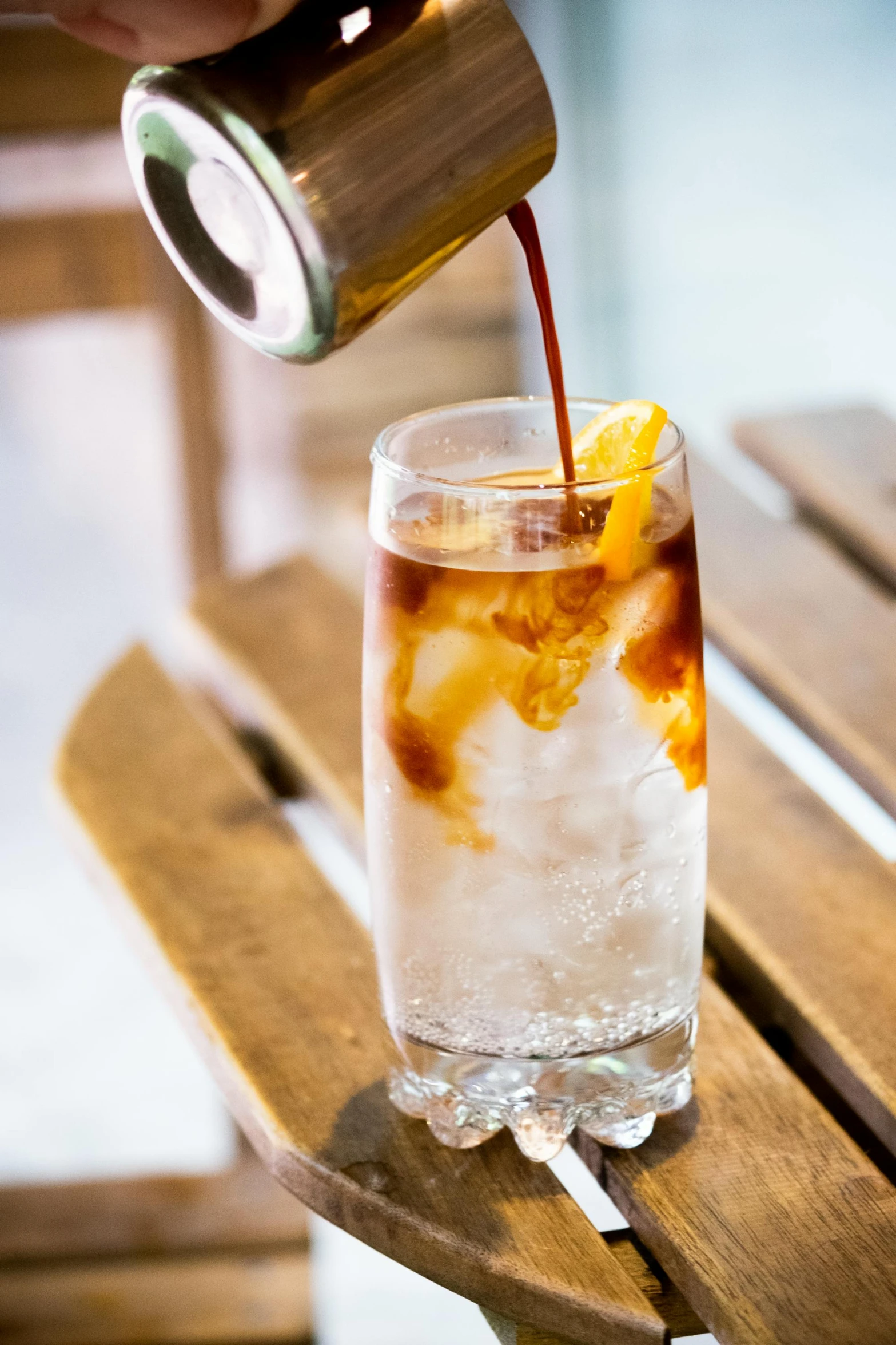 a person pouring orange juice into a glass