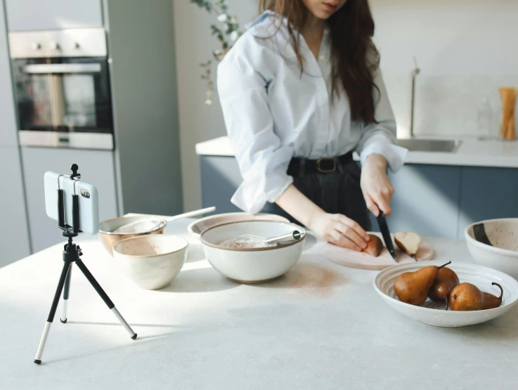 a young woman standing in a kitchen preparing food on a counter